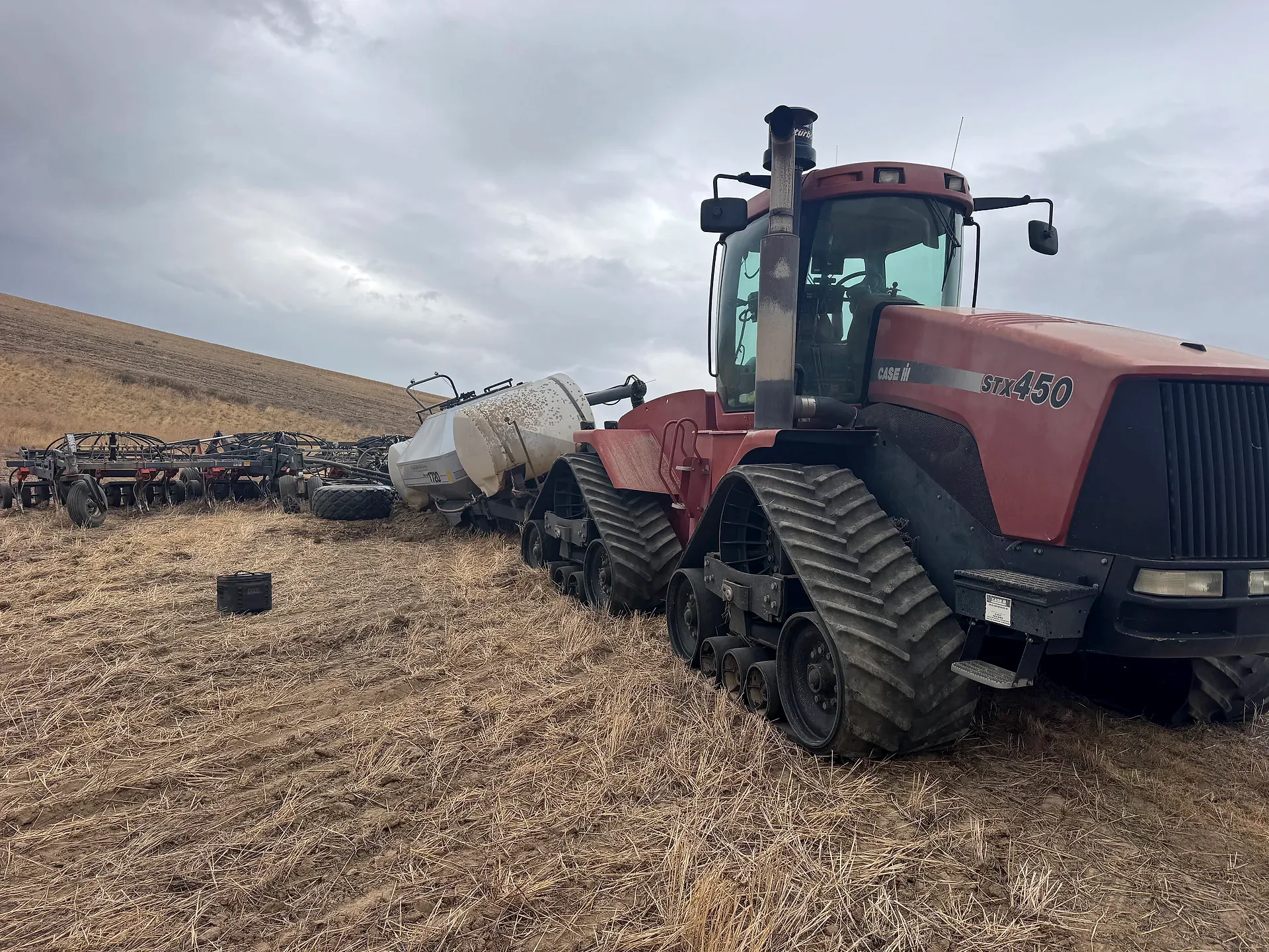 Tracked agricultural tractor and seeding equipment in a dryland field