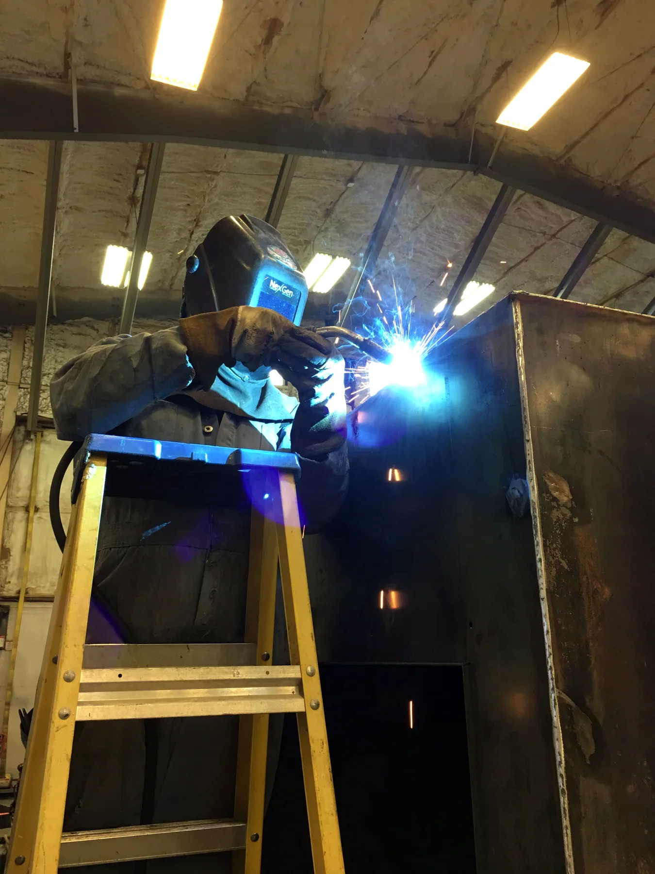 Welder joining a large steel enclosure